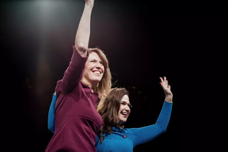 Congresswomen Cindy Axne and Abby Finkenauer waving on stage at the 2019 Liberty & Justice Dinner