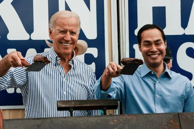 Vice President Joe Biden and Congressman Julian Castro hold steaks up on spatulas as they stand over a large grill