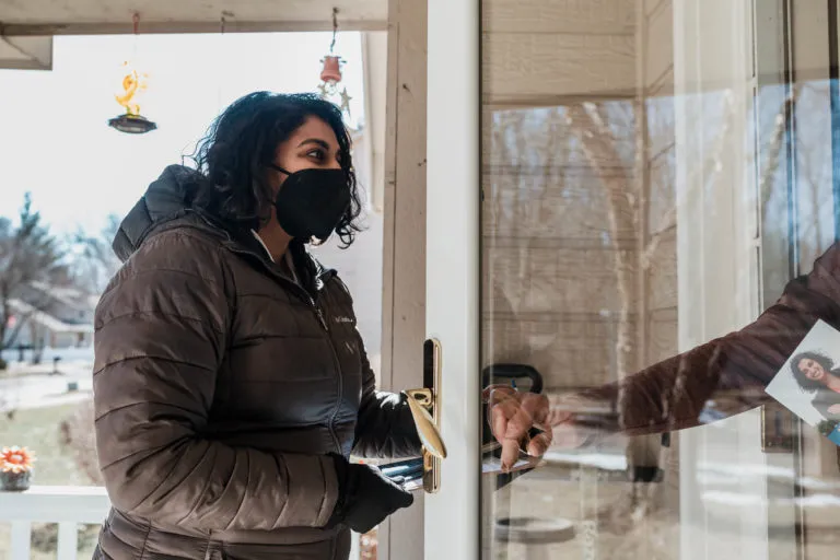 Megan Srinivas speaking with a woman on her doorstep